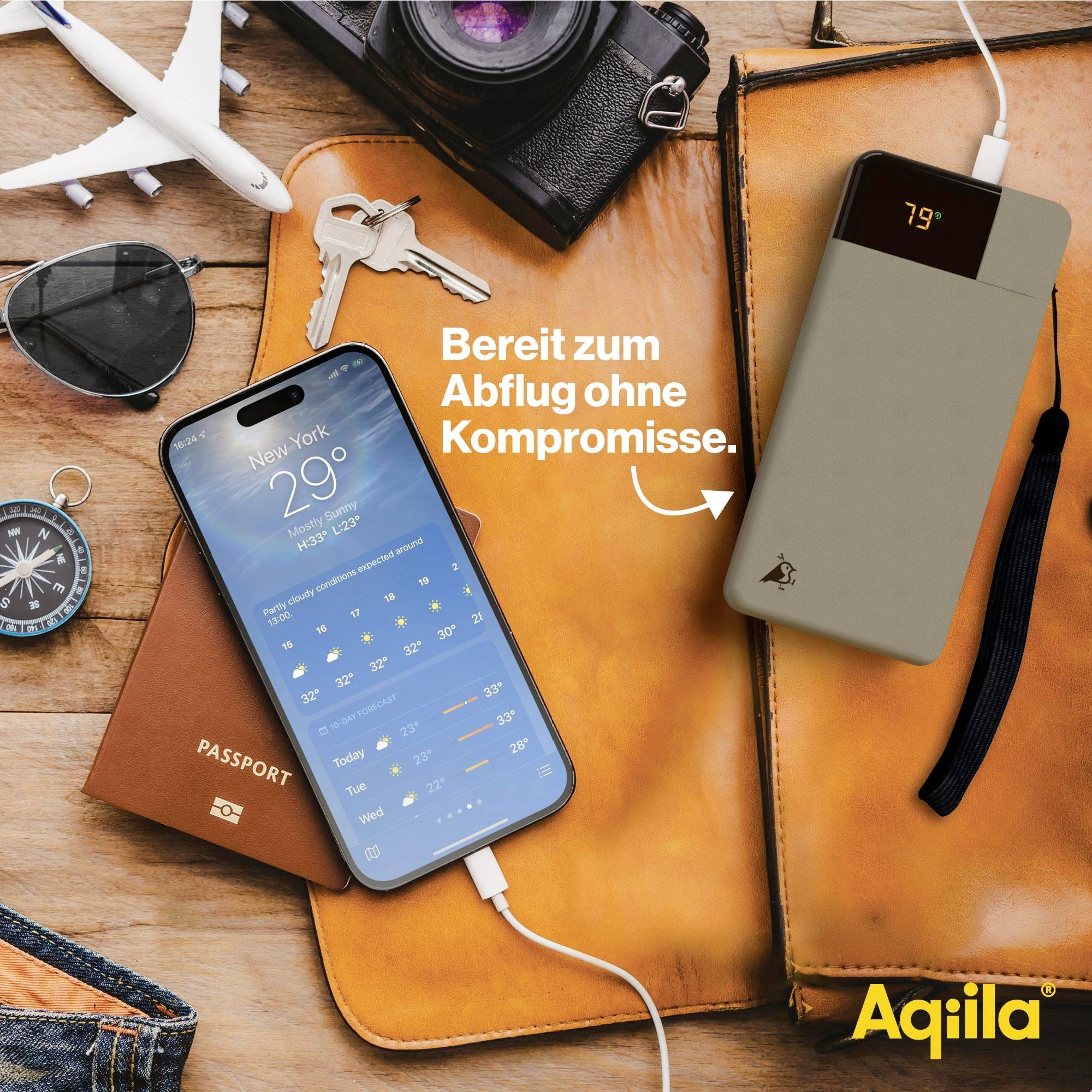 Mobilní telefon je nabíjen pomocí powerbabanky, vedle leží cestovní pas, modelové letadlo a kompas. Text: 'Připraveni k odletu bez kompromisů.'
