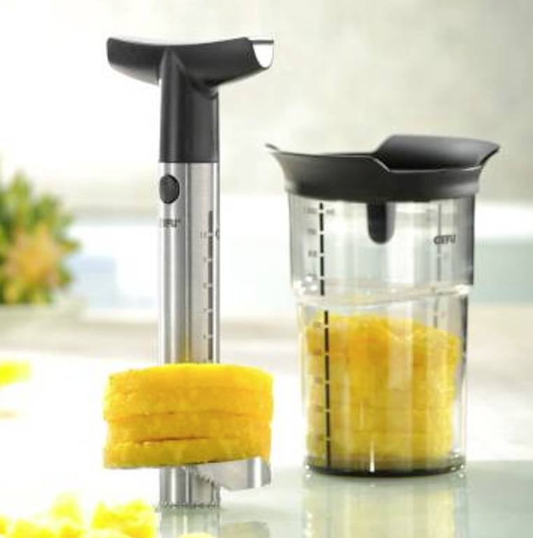 Nůž na ananas z nerezové oceli krájí ananasy na stejnoměrné plátky. Vlevo nástroj na krájení, vpravo nádoba s plátky.