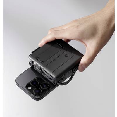 Jedna ruka drží kompaktní černé zařízení, které je umístěno na horní straně smartphonu s vícenásobným fotoaparátem.