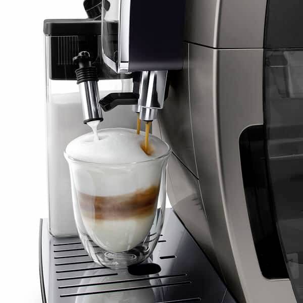Kávový přístroj připravuje Latte Macchiato s krémovou mléčnou pěnou ve skleněné nádobě.