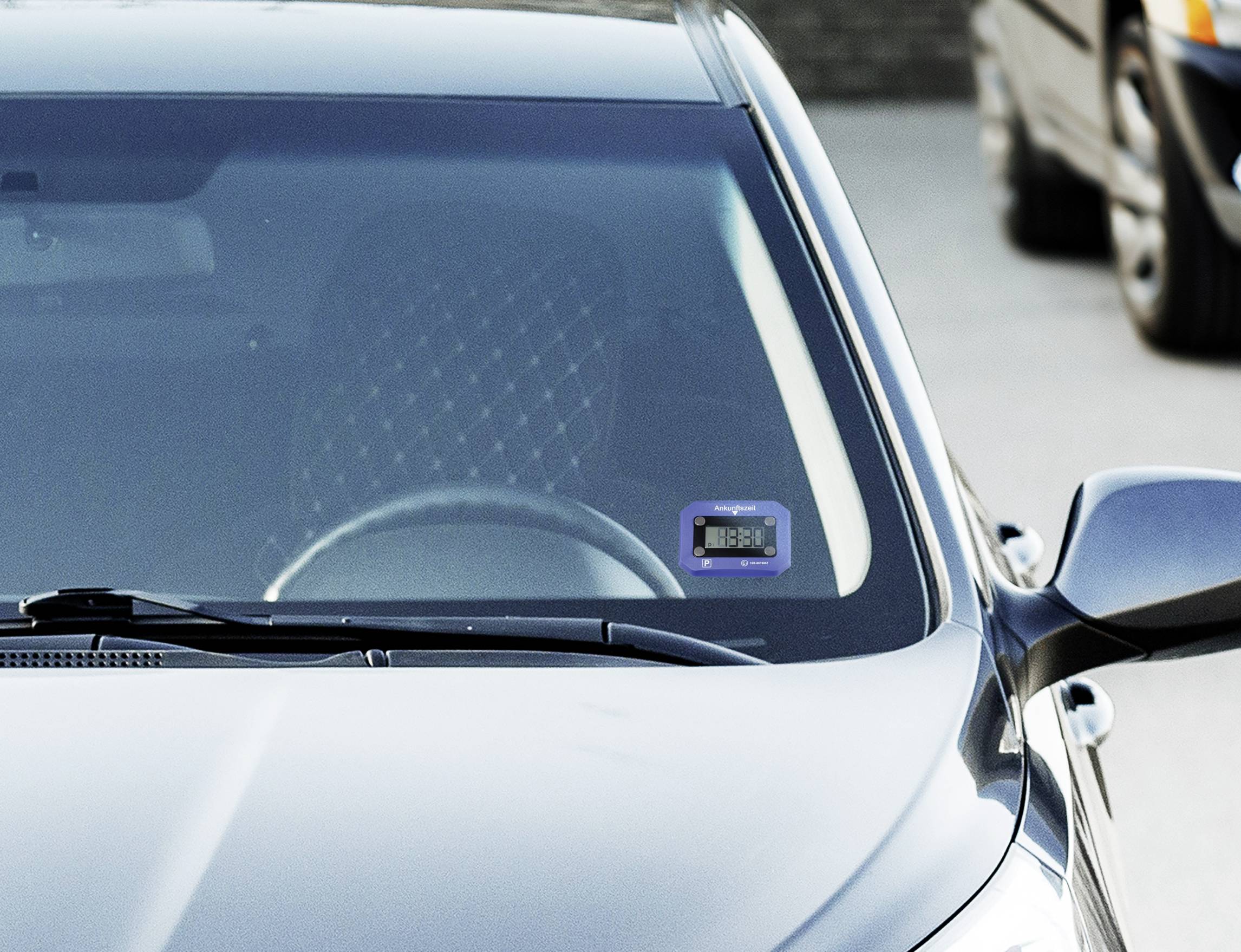 Auto s modrou mýtní kartou připevněnou na čelním skle; popředí zvýrazňuje kartu, která je dobře viditelná zvenku.