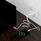 Smartphone je nabíjeno přes USB kabel do elektrické zásuvky. Nabíječka a smartphone leží na dřevěném stole.