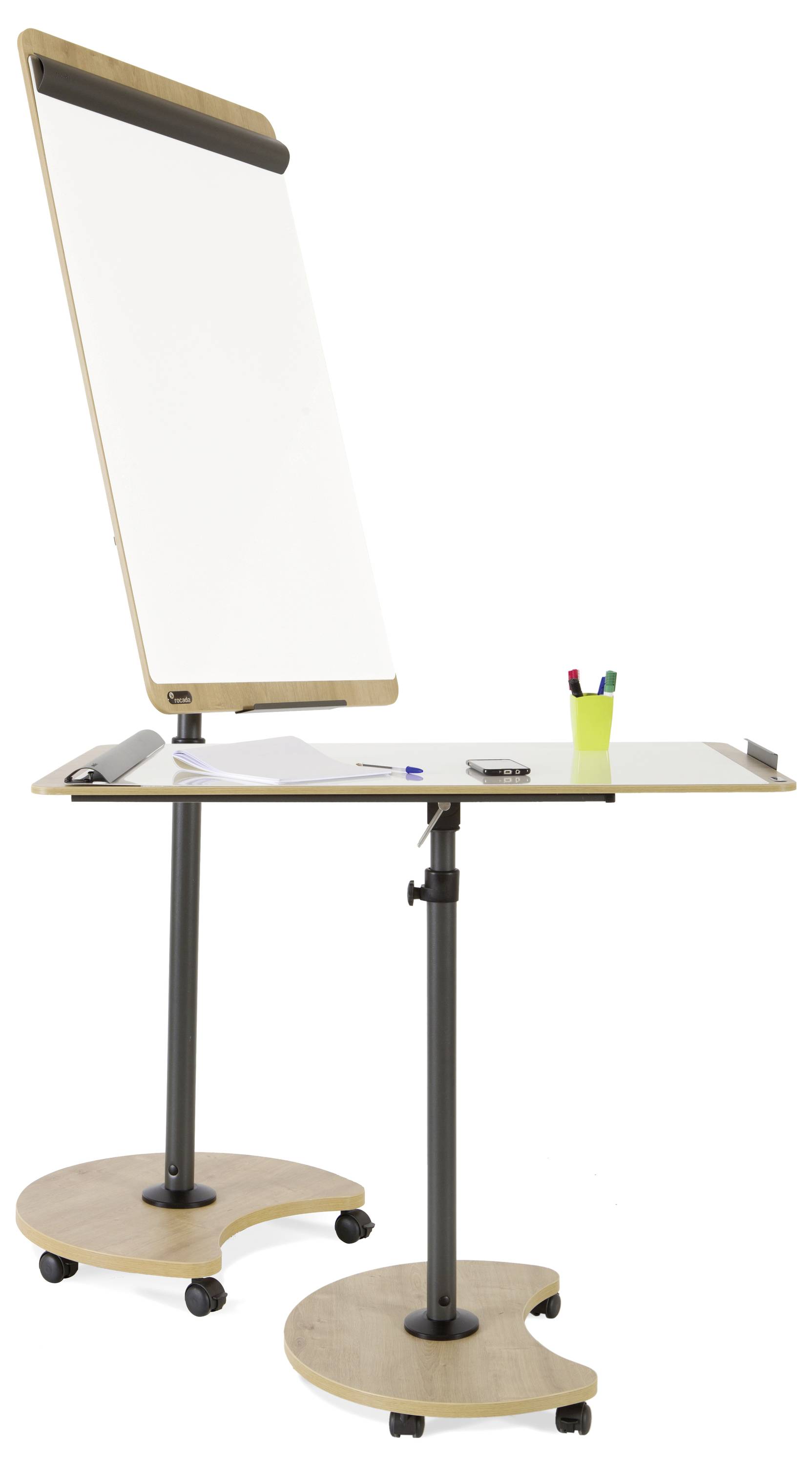 Výškově nastavitelná flipchart s bílou psací plochou na kolečkách, vedle ní tužky v zeleném kelímku na stole.