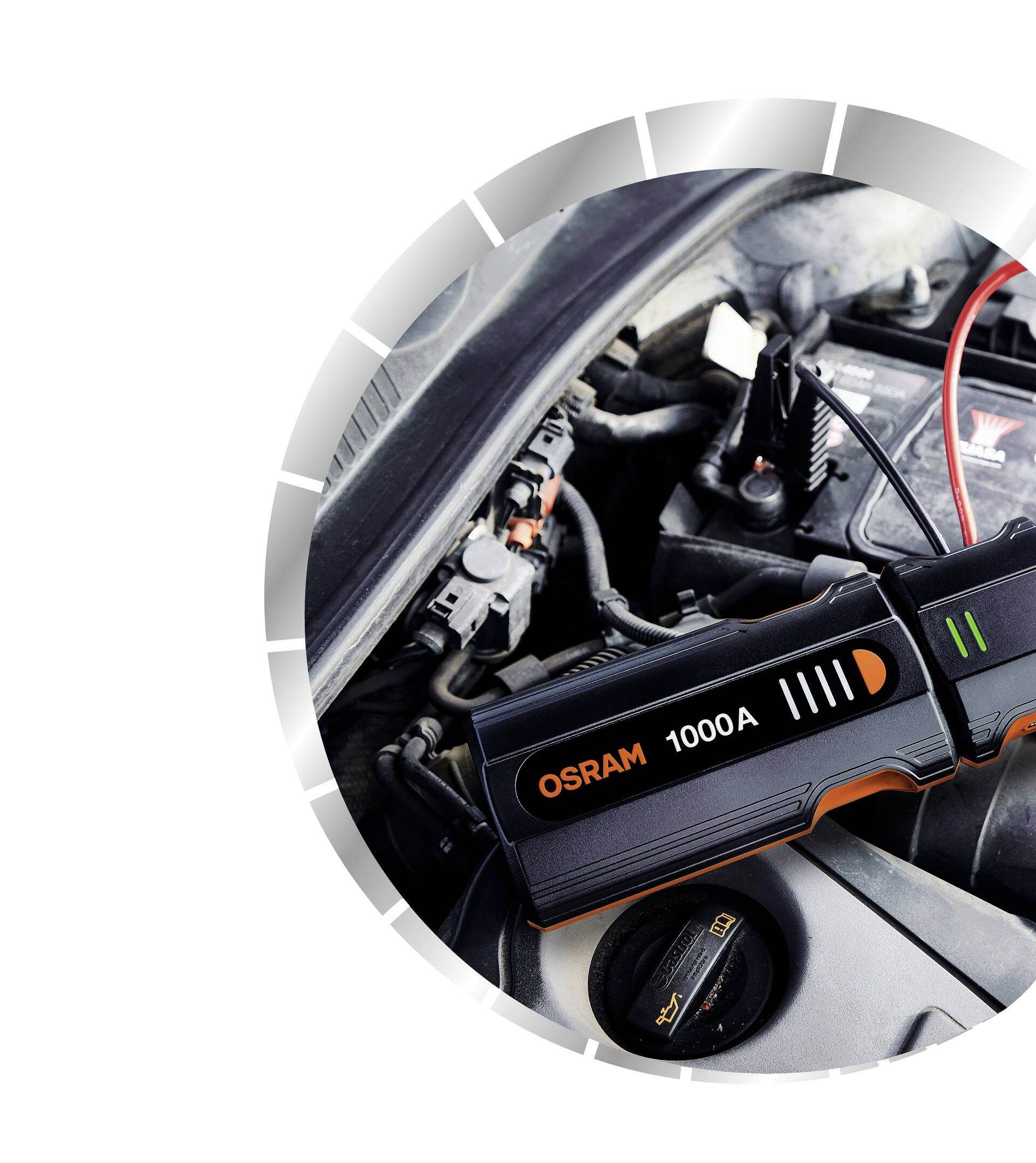 Startovací zařízení pro automobily s nápisem 'OSRAM 1000A' je připojeno k autobaterii za účelem nastartování motoru.