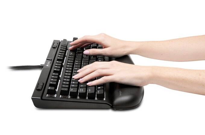 Ruce píšou na černé počítačové klávesnici s ergonomickou opěrkou zápěstí.
