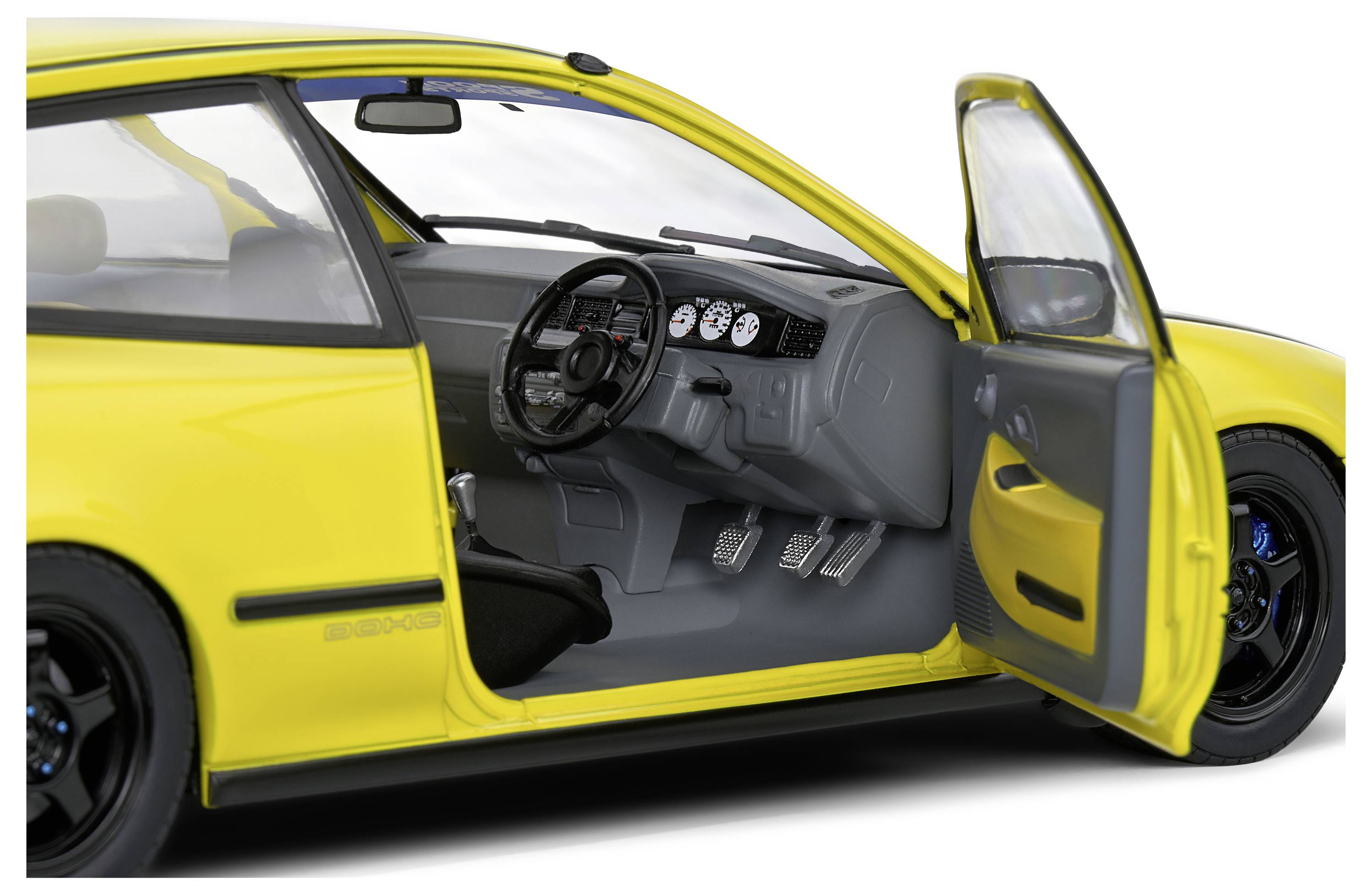 Žluté auto s otevřenými řidičovými dveřmi odhaluje interiér s volantem a přístrojovou deskou.