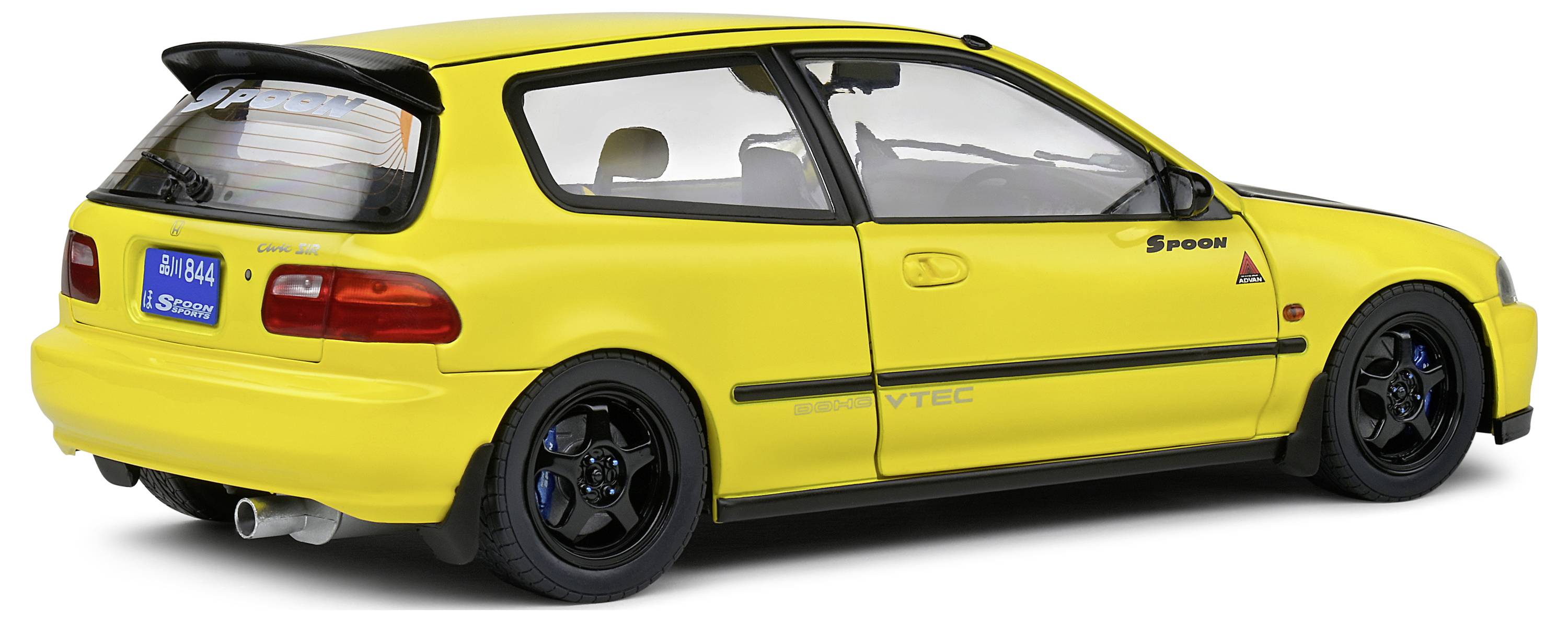 Žluté sportovní auto s černým spoilerem a střechou, modrými ráfky a nápisem 'Spoon'. Registrační značka s japonskými znaky.