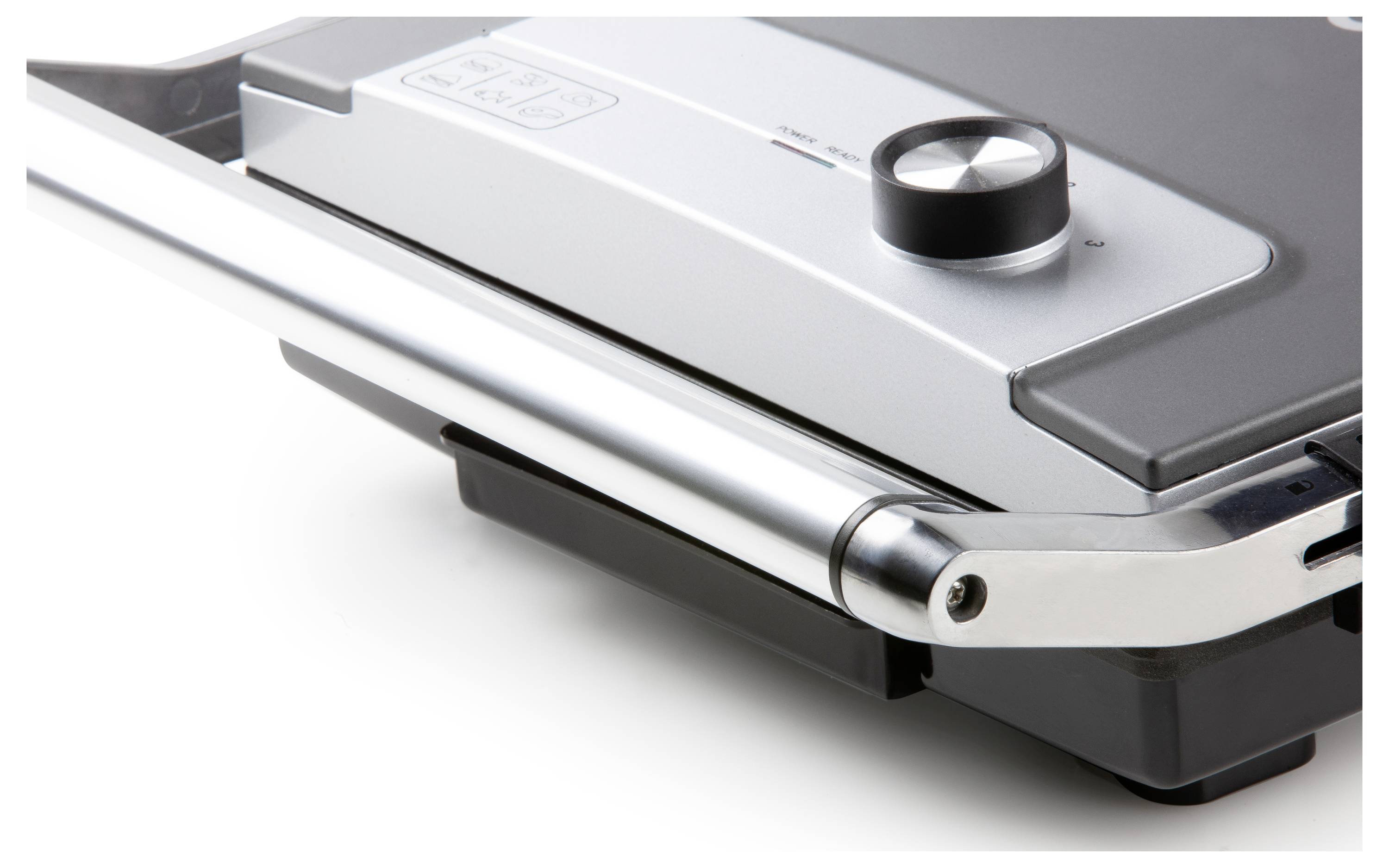 Stříbrný elektrický gril s černým otočným knoflíkem a rukojetí. Gril je zobrazen z části zavřený.