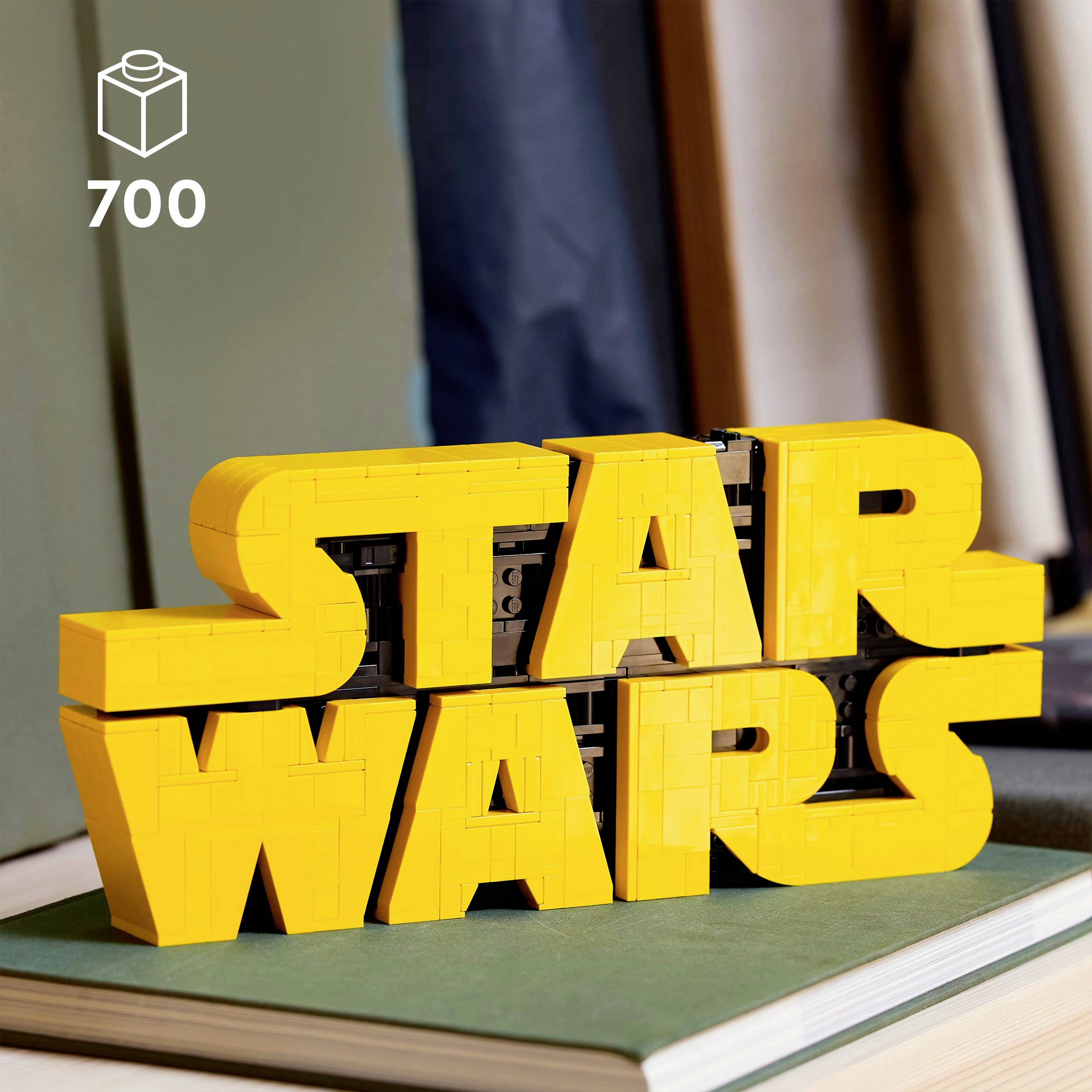Žluté logo 'Star Wars' vytvořené z kostek leží na knize. Vlevo nahoře je symbol označující 700 dílků.