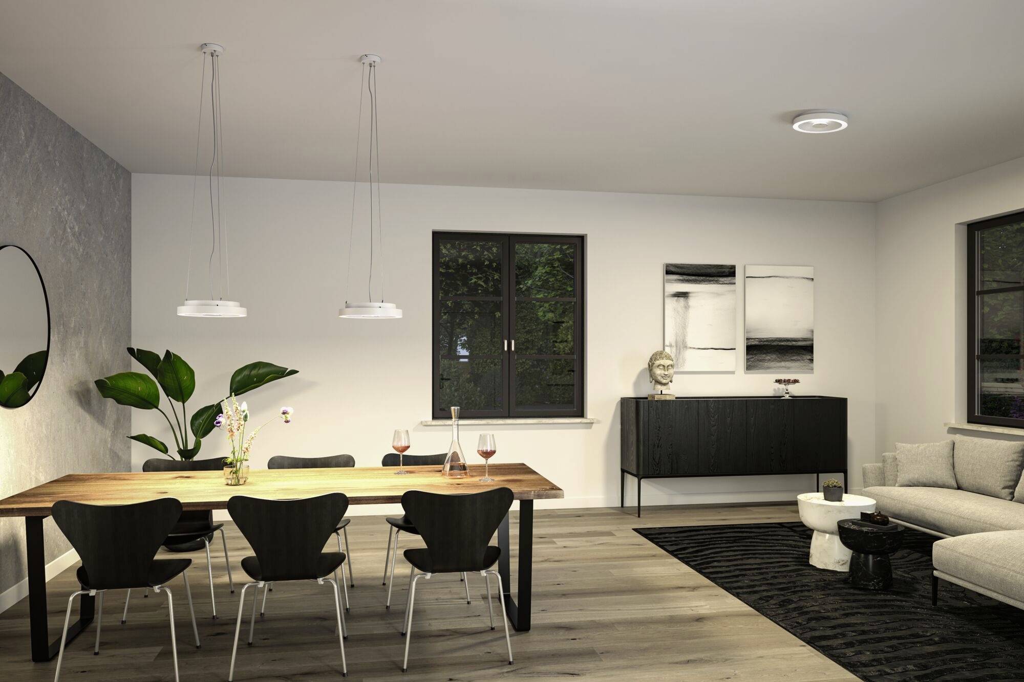 Jídelna s dřevěným stolem a šesti černými židlemi, moderní osvětlení. V pozadí kredenc a stylová nástěnná dekorace.