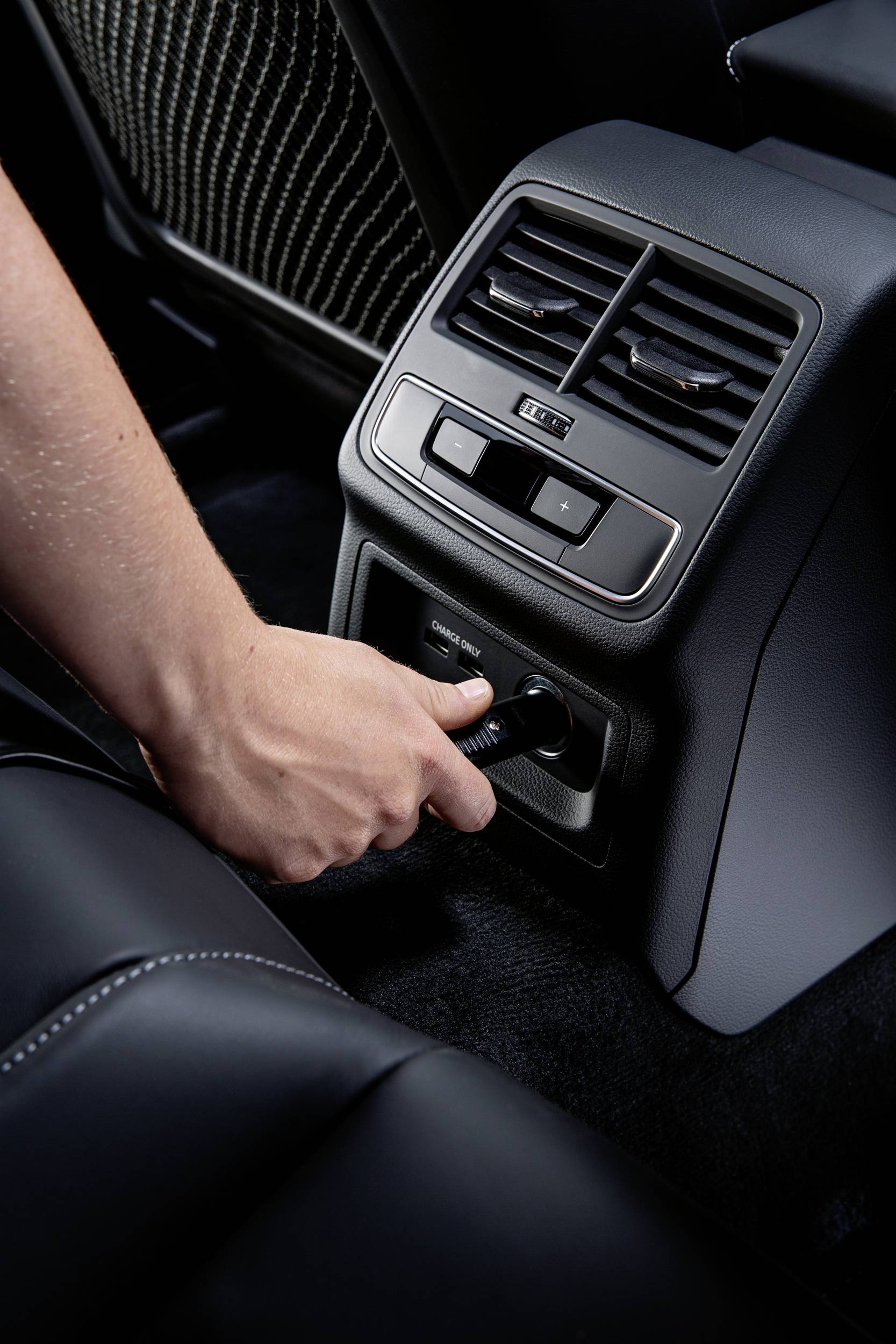 Ruka zapojuje kabel do zásuvky na zadním sedadle automobilu.
