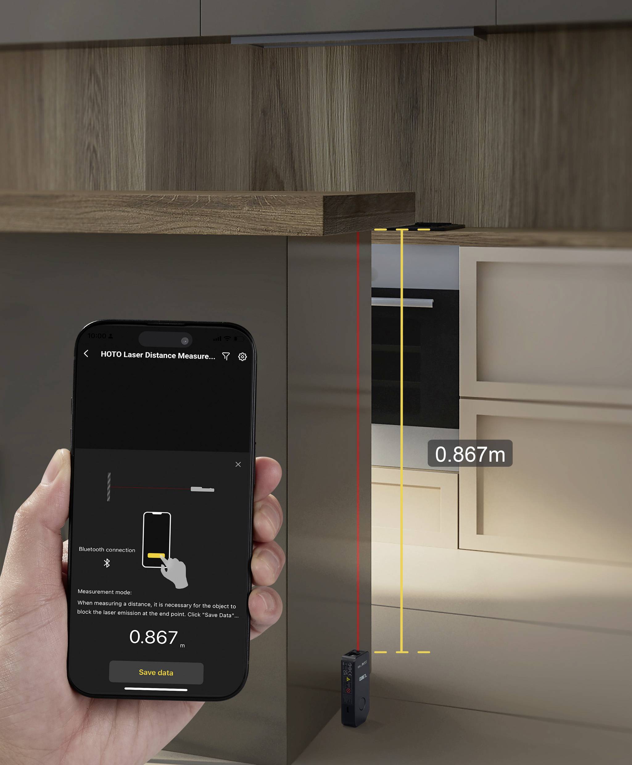Jedna ruka drží smartphone zobrazující měřicí aplikaci. Laserový dálkoměr měří vzdálenost 0,867 metru od skříně k podlaze.