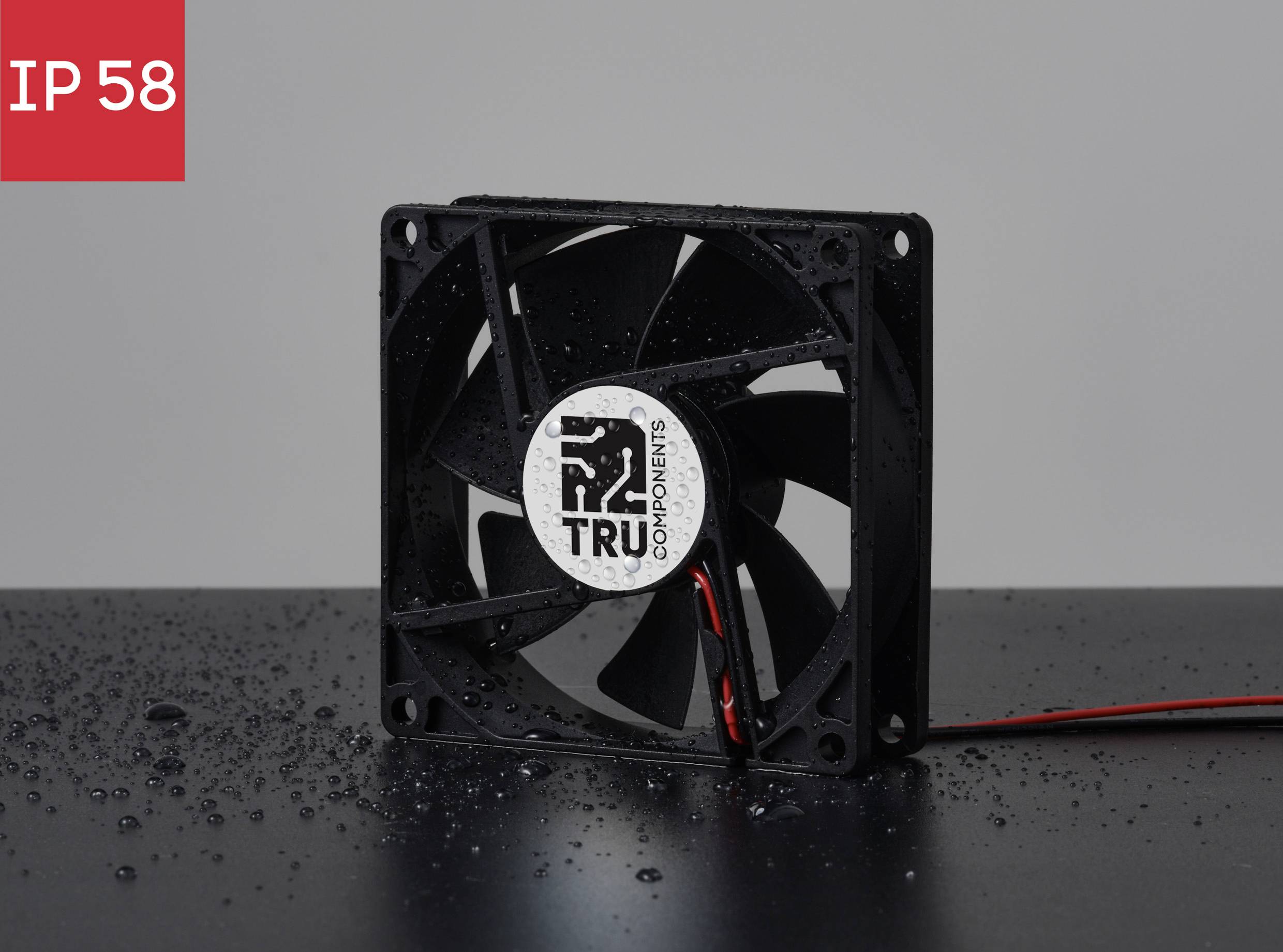 Černý počítačový ventilátor s kapkami vody, označený štítkem "IP 58", na černém podkladu před šedým pozadím.