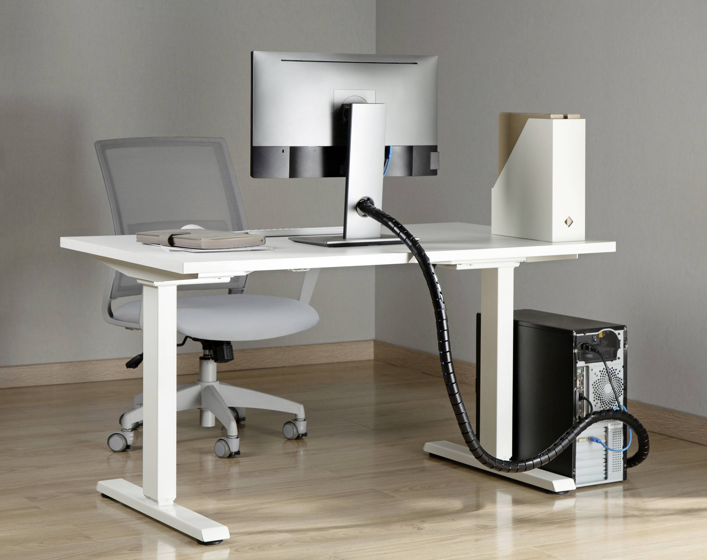 Moderní, ergonomický psací stůl s nastavitelnou kancelářskou židlí. Na stole stojí monitor a složka.