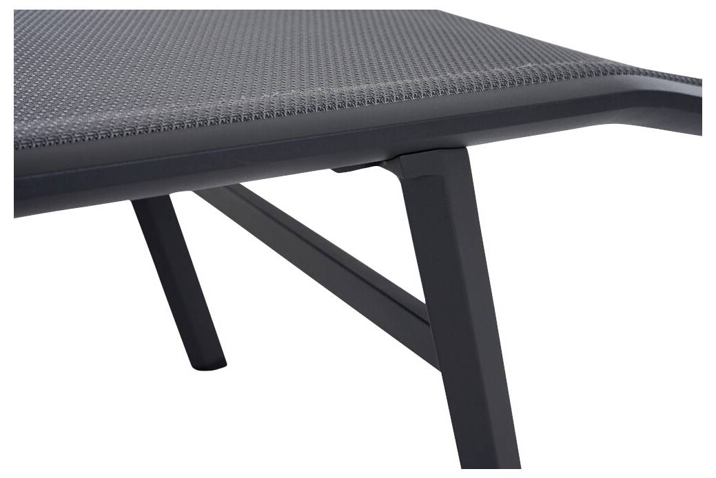 Výřez ukazuje stylový stůl s minimalistickým designem, složený z tmavého kovového rámu a perforovaného povrchu.