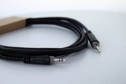 Černý audiokabel se dvěma 3,5mm konektory na bílém pozadí.
