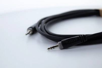 Černý audiokabel s 3,5mm konektorem na bílém pozadí.