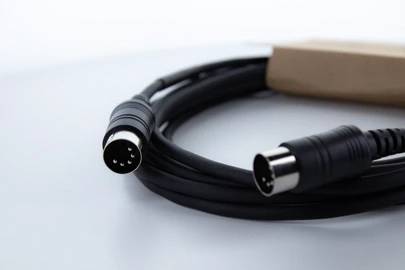 Černý MIDI kabel s pětikolíkovými konektory leží na bílém podkladu.