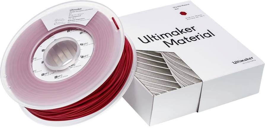 Role s červeným 3D tiskařským vláknem vedle bílé krabice s nápisem 'Ultimaker Material'.