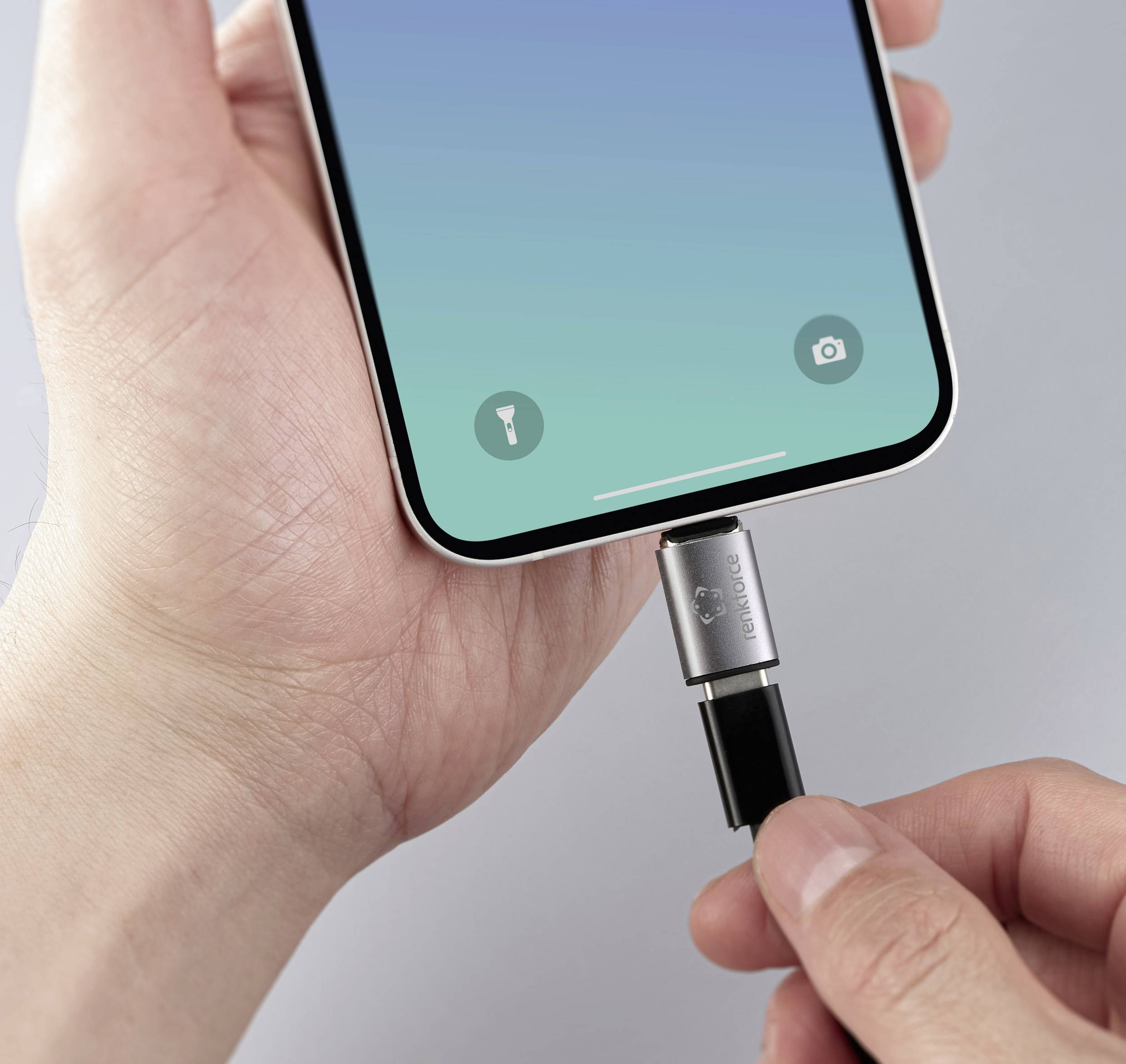 Jedna ruka drží smartphone s připojeným USB kabelem. Druhá ruka kabel zapojuje. Jsou viditelné symboly pro svítilnu a fotoaparát.