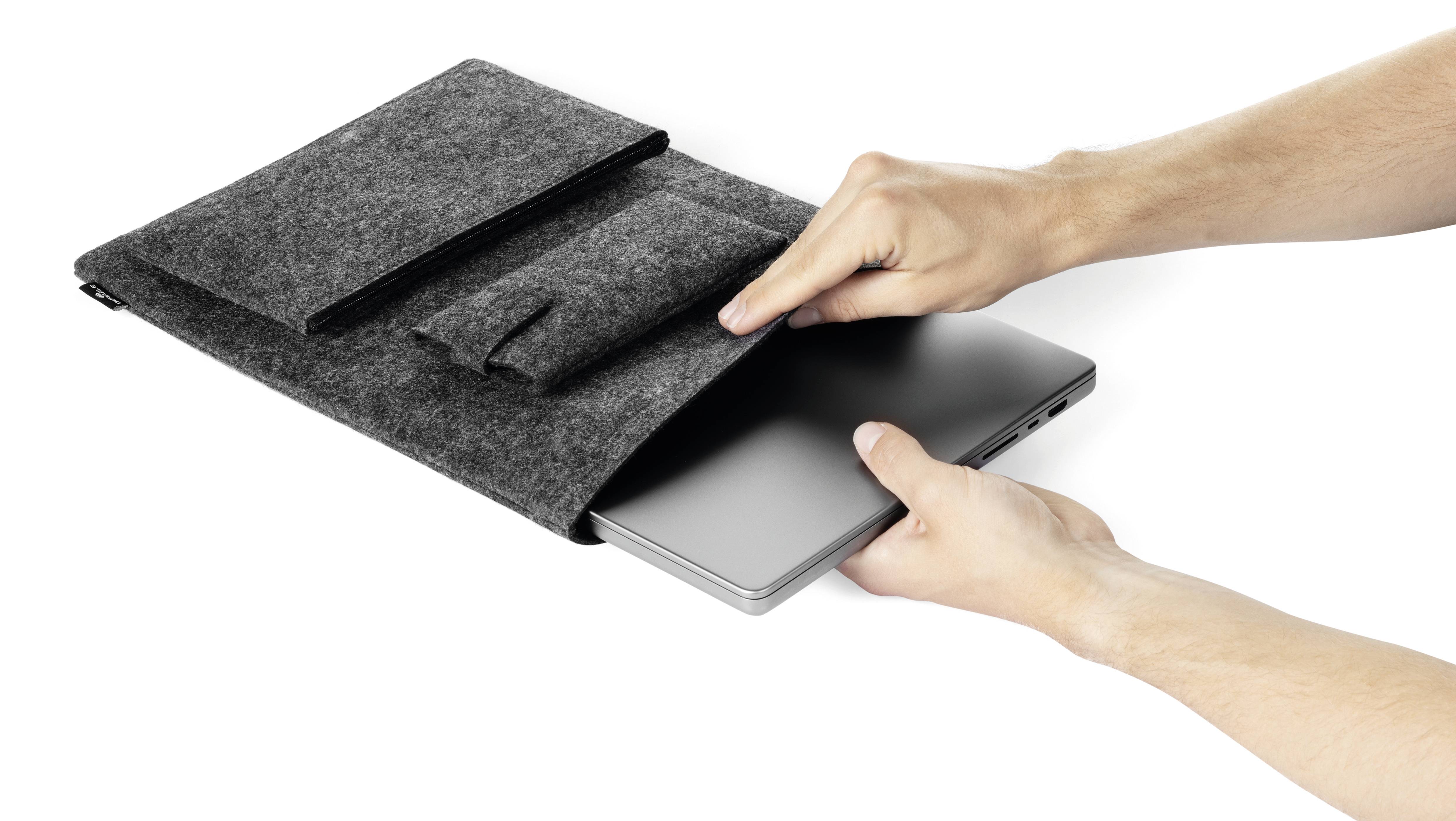 'Osoba vkládá laptop do šedého plstěného obalu s dalšími kapsami.'