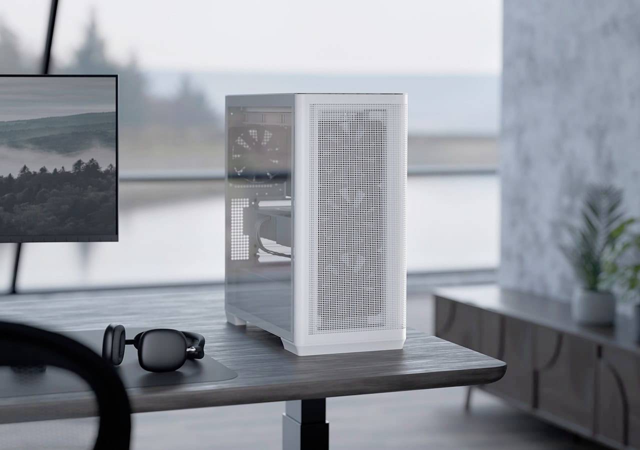 Moderní pracovní prostor s bílou, minimalistickou počítačovou věží na stole vedle monitoru a sluchátek, s klidným výhledem do exteriéru.