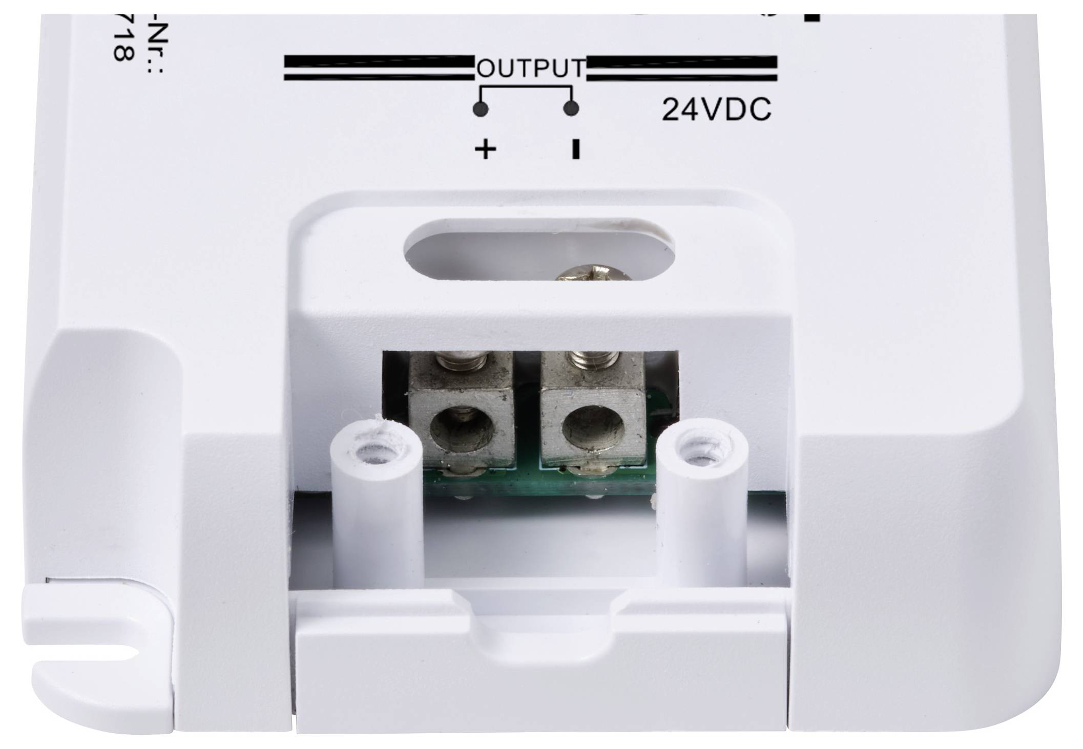 Bílé elektrické zařízení s přípojkami, označené 'OUTPUT' a '24VDC', zobrazuje kladné a záporné kontakty pro napájení.