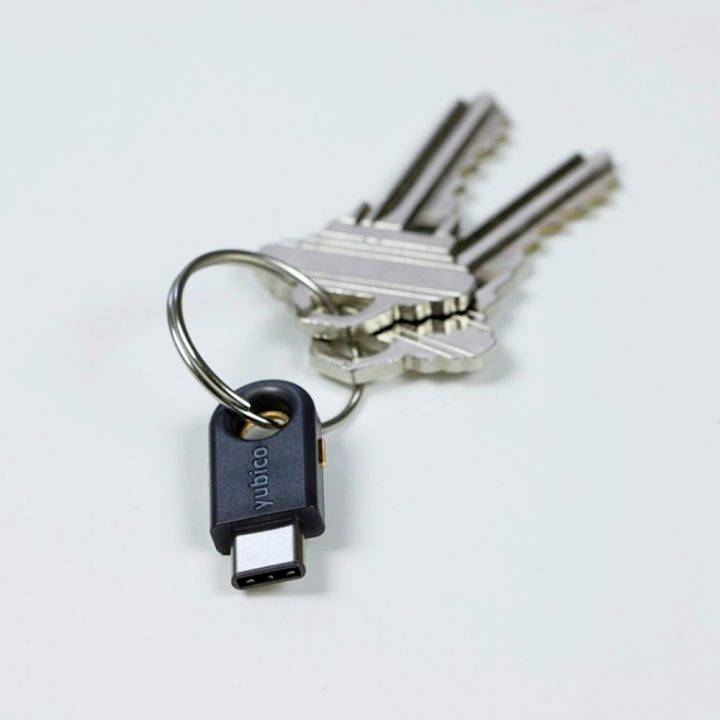 Svazek klíčů s několika kovovými klíči. Černý USB bezpečnostní přívěsek je připevněn na kroužku.