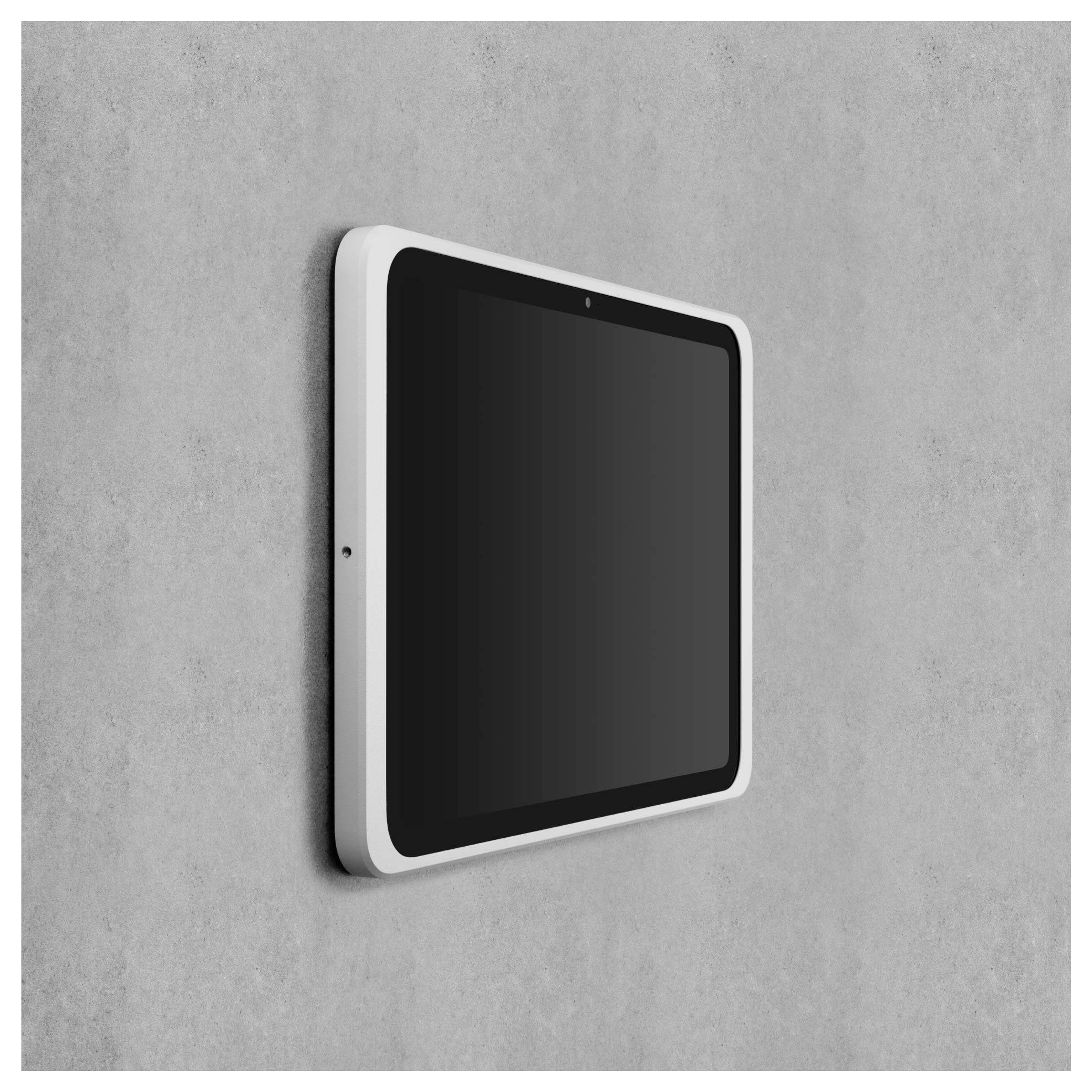 Černý tablet s bílým rámečkem je připevněn na šedé zdi. Je umístěn v horizontální poloze.