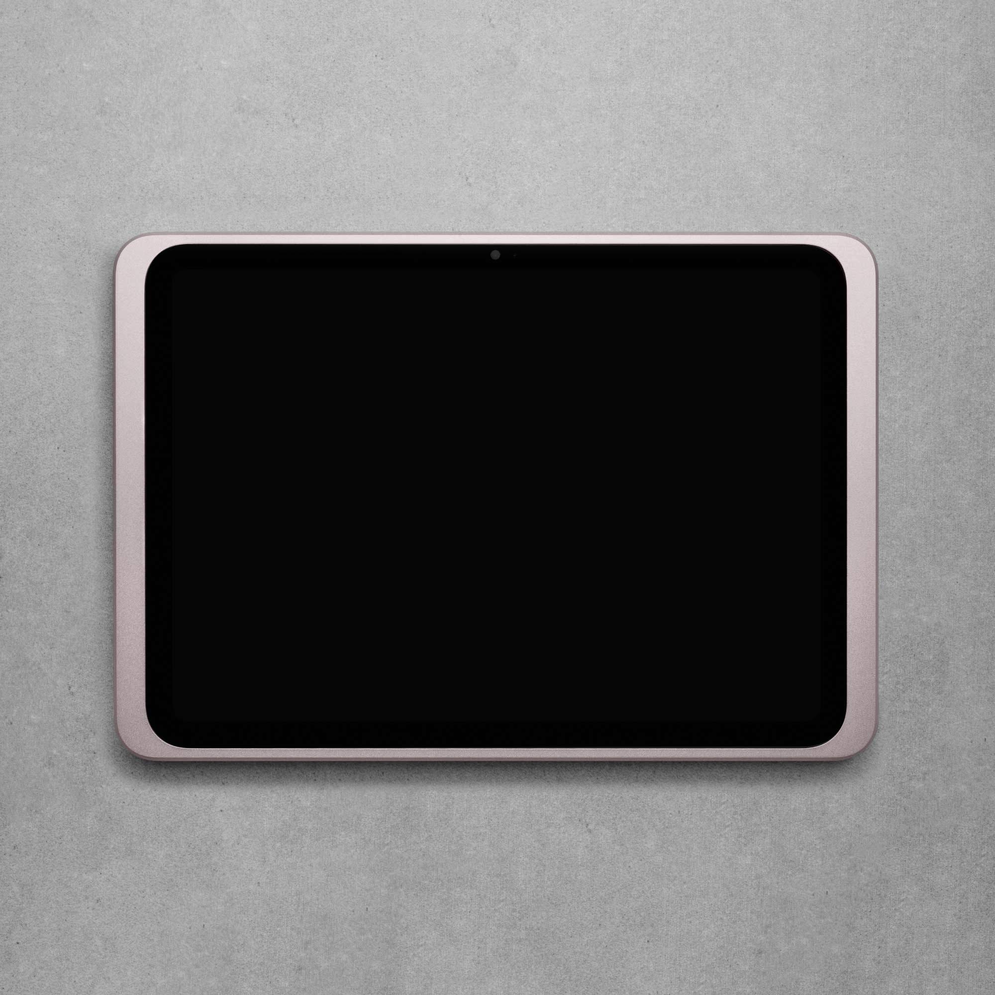 Tablet s černou obrazovkou na šedém povrchu.