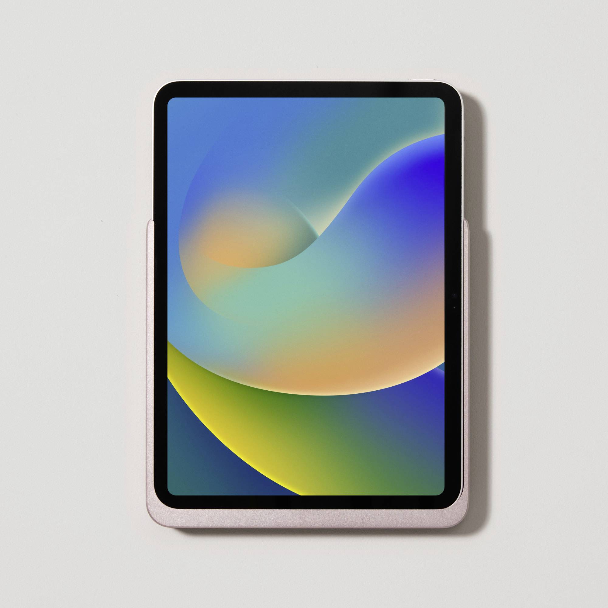 Tablet s barevným abstraktním pozadím na obrazovce leží na světlém povrchu.