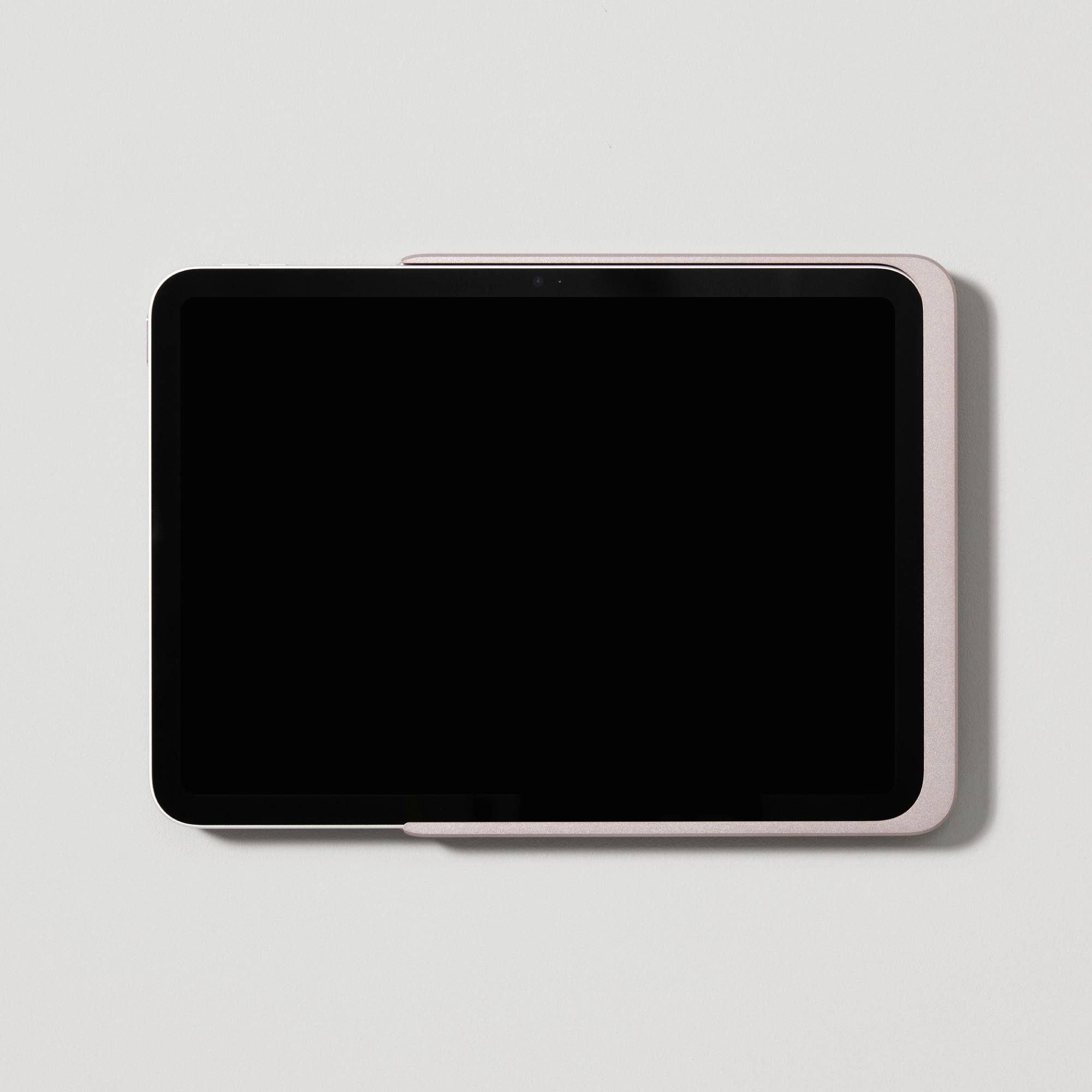 Tablet s černou obrazovkou leží na bílém povrchu. Má zaoblené rohy a tenký rámeček.