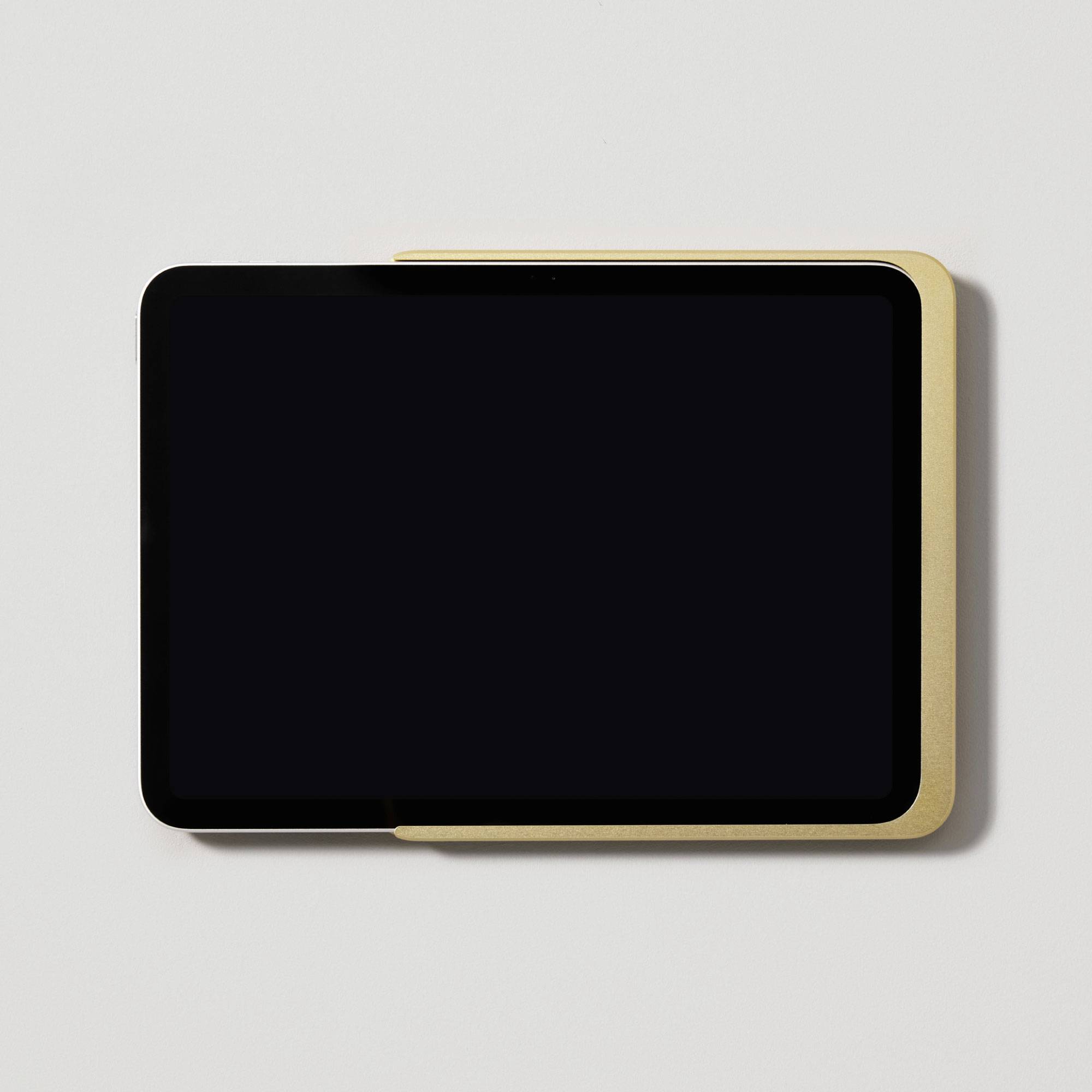Černý tablet na stole, částečně zakrytý krémovým předmětem. Povrch je tmavý a lesklý.