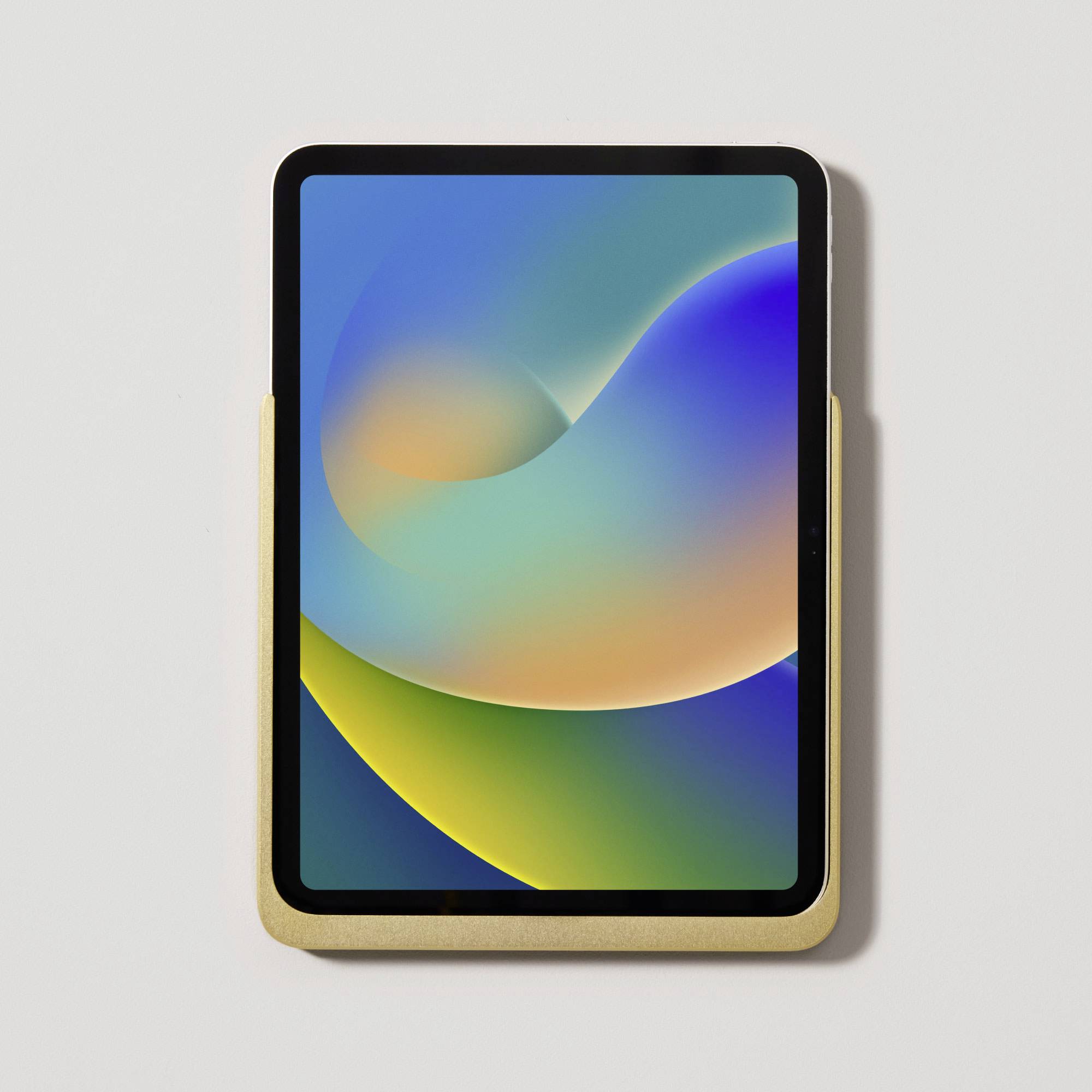 Tablet s barevným abstraktním pozadím leží na světlém podkladu. Displej zobrazuje plynulé barevné přechody.