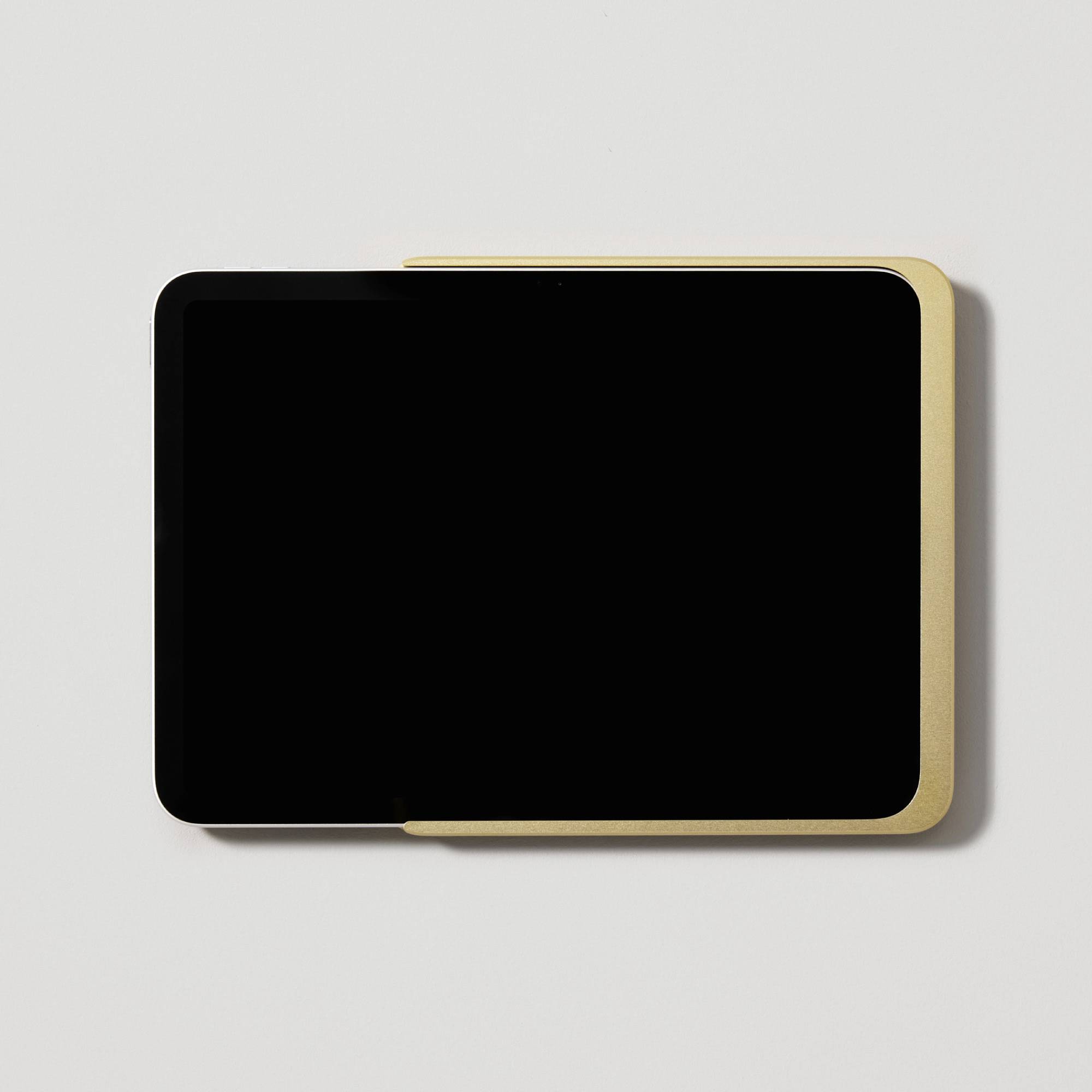 Černý tablet se zlatým okrajem leží na bílém pozadí.