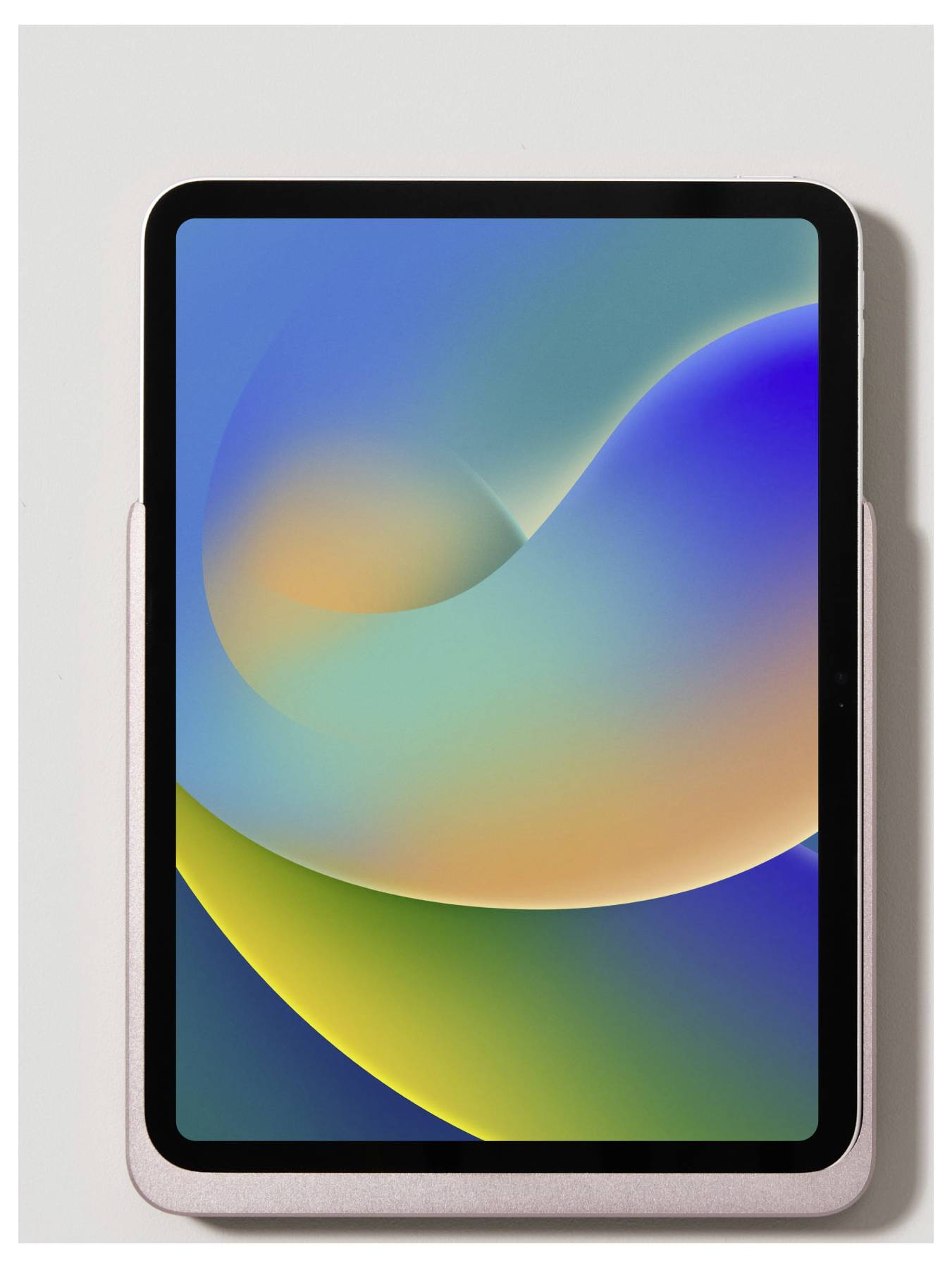 Tablet s abstraktním barevným pozadím v modrých, zelených a oranžových tónech leží na světlém povrchu.