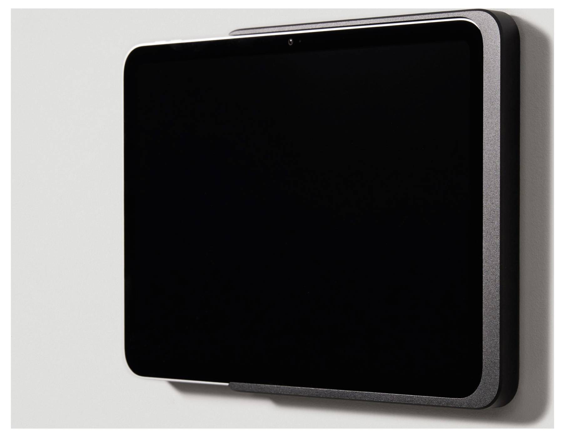 Černé elektronické zařízení namontované na stěně. Vypadá jako tablet umístěný v držáku.