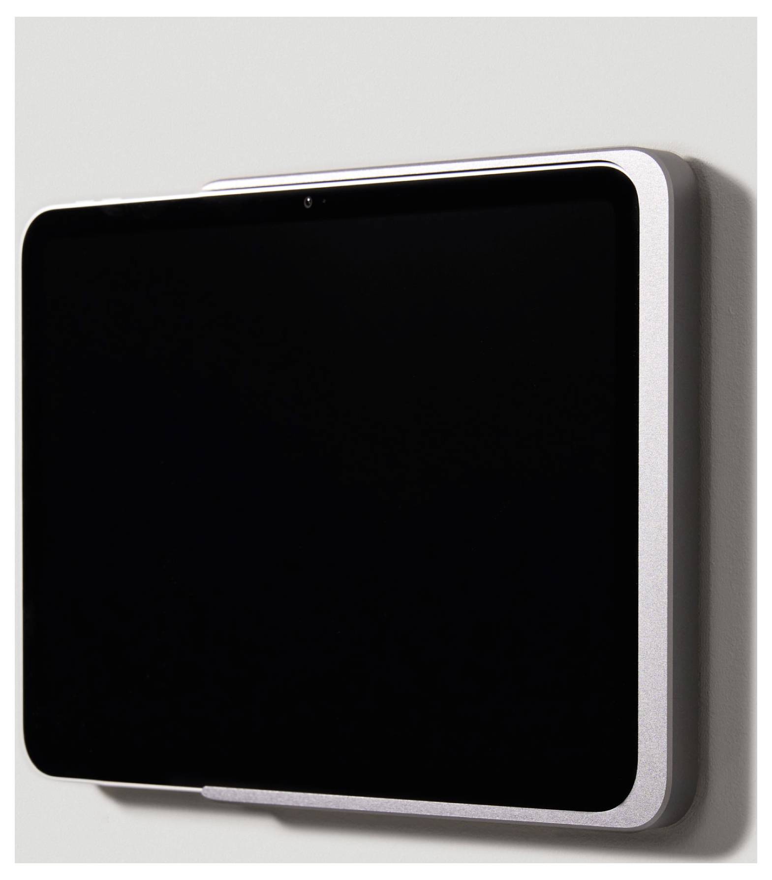 Černý tablet se stříbrným rámečkem je upevněn na stěně. Obrazovka je vypnutá a neodrráží žádné světlo.