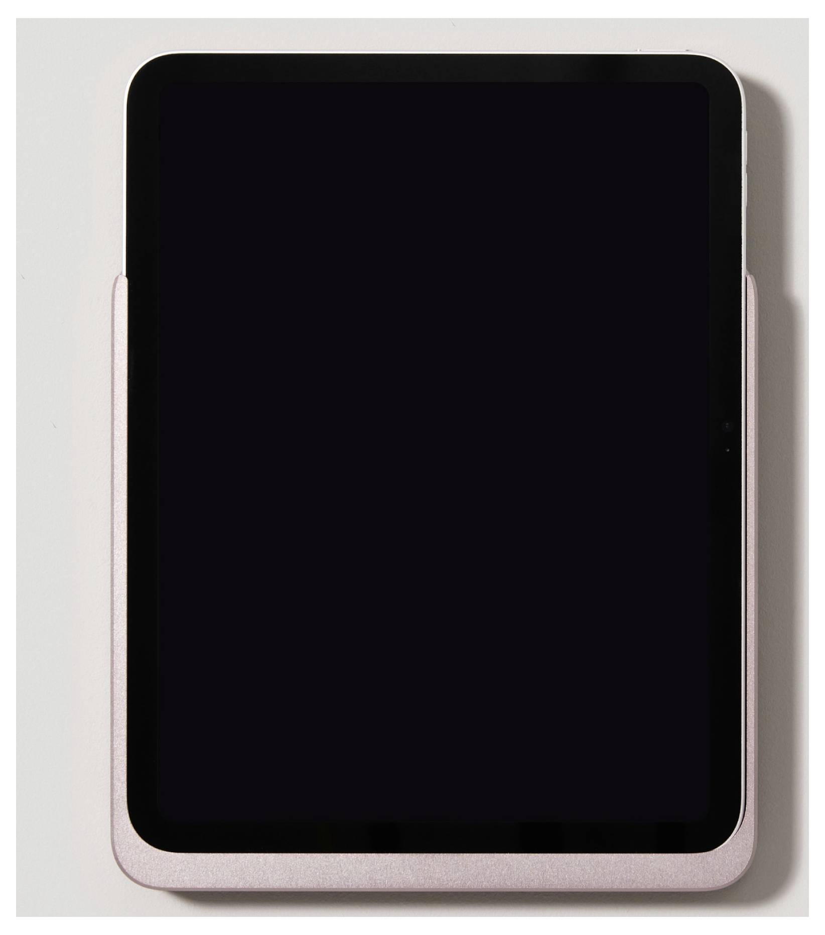 Tablet s černou obrazovkou leží na bílém povrchu. Je zasazeno do úzké, růžové obaly.
