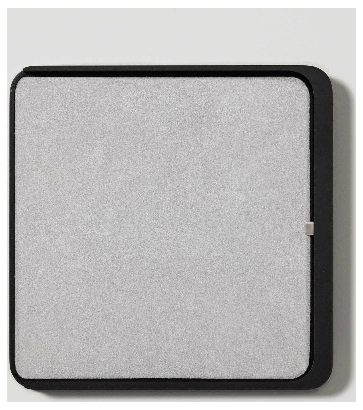 Obdélníkový, tenký kryt chytrého termostatu s minimalistickým designem, černým rámečkem a stříbrnou přední stranou.