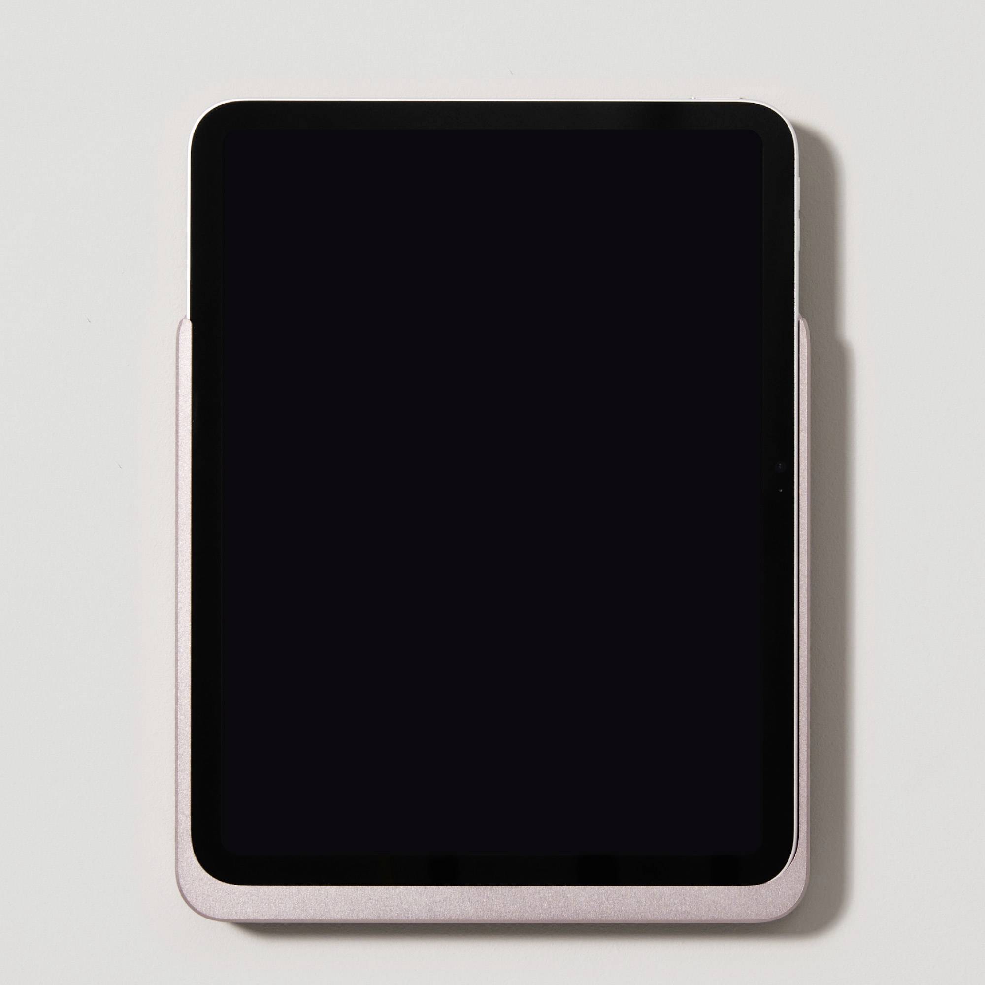 Tablet s černou obrazovkou leží na bílém povrchu.