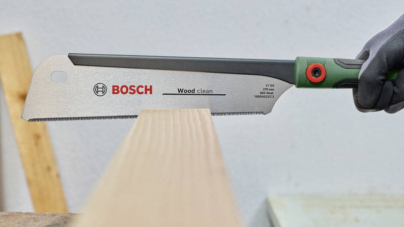 Ruční pila značky Bosch s listem označeným jako 'Wood clean' se používá k řezání dřevěné desky.