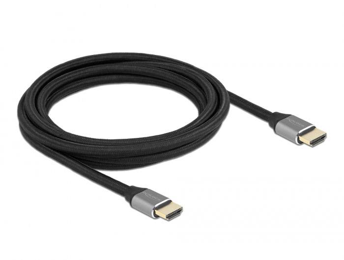Černý HDMI kabel se dvěma zlatými konektory. Kabel je svinutý a leží na bílém povrchu.