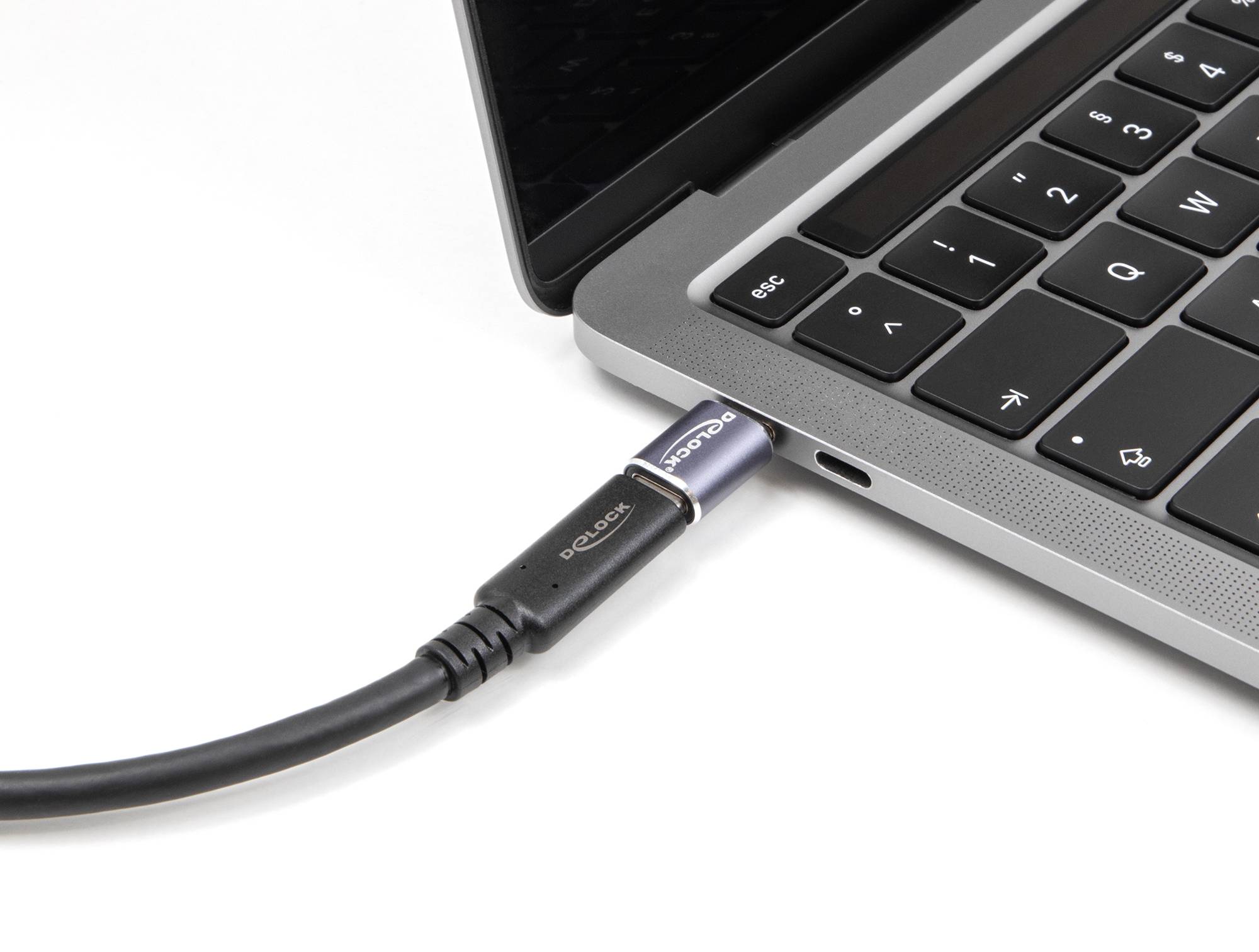 Notebook zblízka s USB kabelem zapojeným na levé straně, který vytváří připojení ke zdroji napájení.