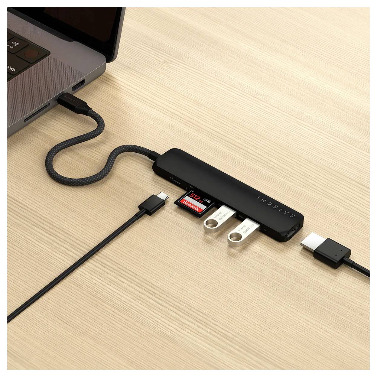 USB hub s několika porty, včetně USB a slotů pro SD karty, připojený k notebooku na dřevěném stole.