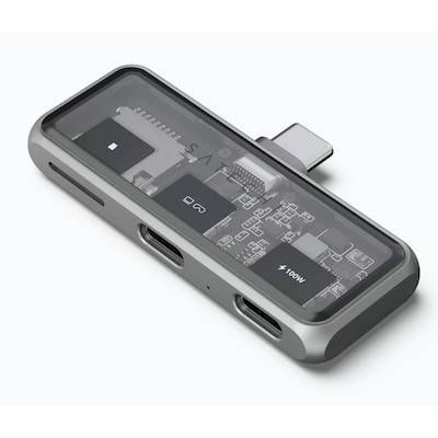 Stříbrný USB-C hub s průhledným tělem, který odhaluje vnitřní elektrické obvody. Obsahuje různé konektory.