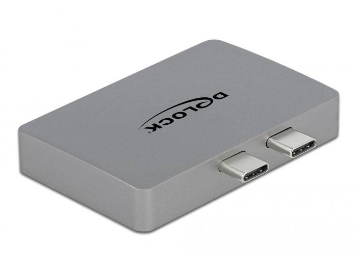 Externí adaptér pro pevný disk se dvěma USB-C porty, stříbrné šasi s logem značky na horní straně.