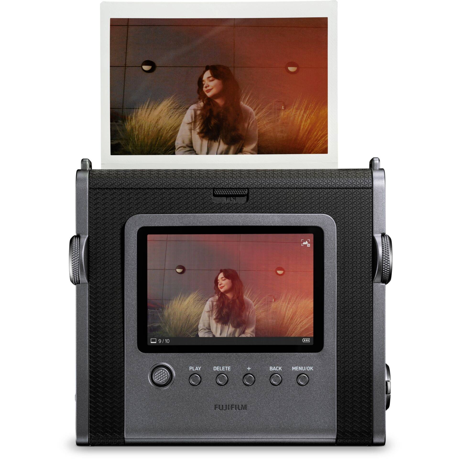 Fotografie zachycuje usmívající se osobu sedící před stěnou s dekorativními světly. Je zde viditelná polaroidní fotografie.