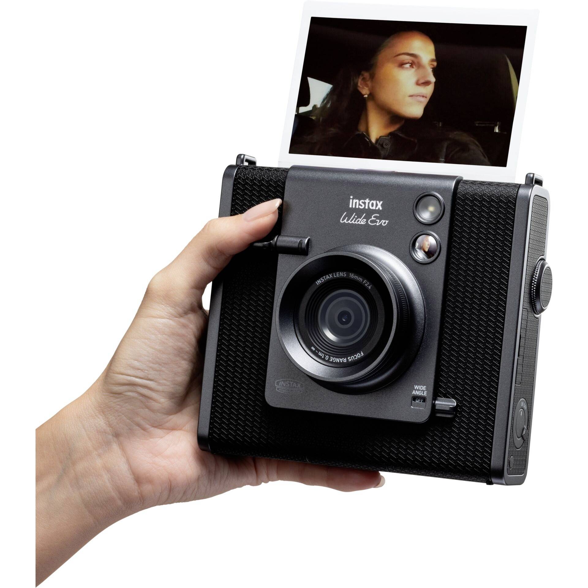 Ruka drží instax fotoaparát, který tiskne okamžitou fotografii ženy v autě.