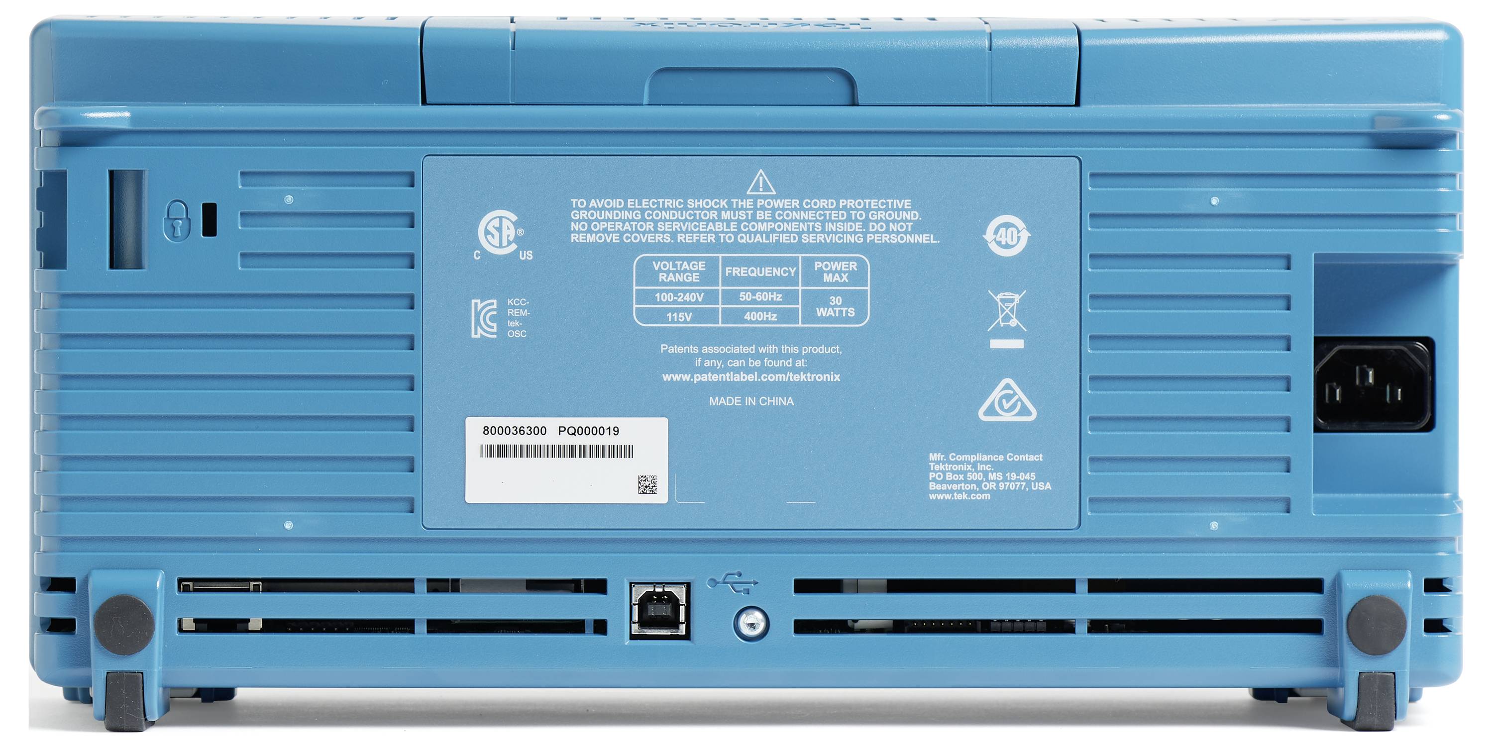 Zadní strana elektronického zařízení v modré barvě s různými konektory, bezpečnostní nálepkou a čárovým kódem.